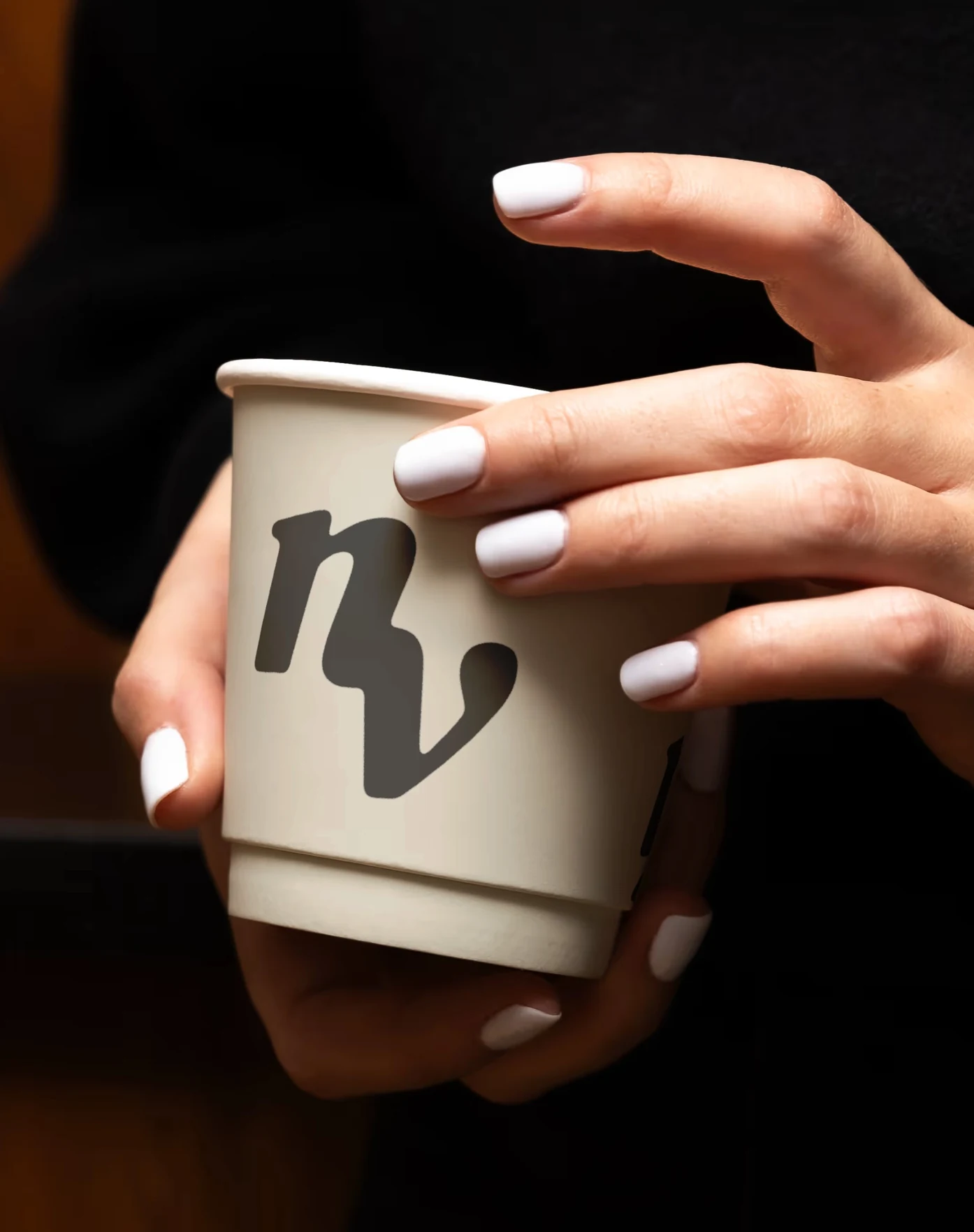 A takeaway cup carrying the nave mark, held in both hands